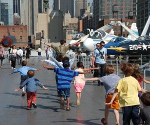Kids running outside all arms out like airplanes. Intrepid Museum
